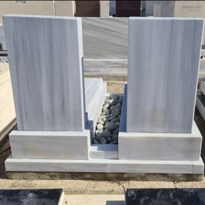 מצבות שיש עם חלוקי נחל ביניהן בבית קברות