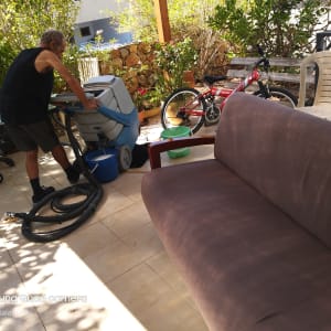 אדם מנקה ספה עם מכונת ניקוי וחומרי ניקוי