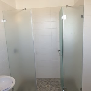 מקלחון עם דלתות זכוכית חלבית ורצפת אריחים מעוצבת