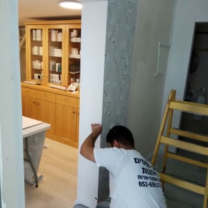 אדם מתקין טפט פרחוני על קיר פנימי