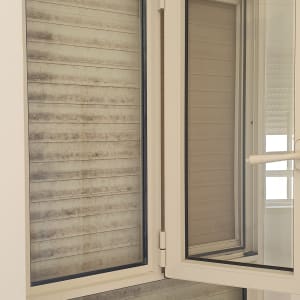 חלון עם תריסים מלוכלכים באבק ולכלוך