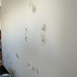 קיר עם תיקוני שפכטל ודלי צבע על הרצפה