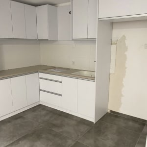 מטבח ריק עם ארונות לבנים ורצפה נקייה