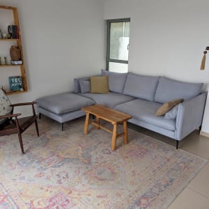 ספה אפורה עם כריות על שטיח צבעוני