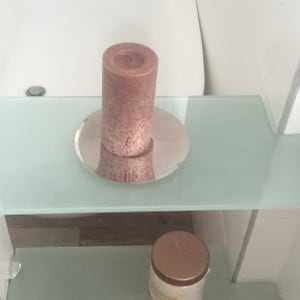 מדף זכוכית עם נר ורוד על צלחת