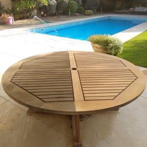 שולחן עץ עגול ליד בריכת שחייה בגינה