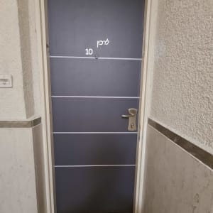 דלת מתכת אפורה עם ידית כסופה ומספר 10