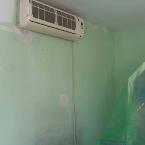 קיר צבוע בירוק עם תיקוני צבע ויריעות פלסטיק