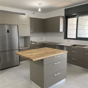 מטבח מודרני עם מקרר, ארונות ומשטח עבודה מעץ