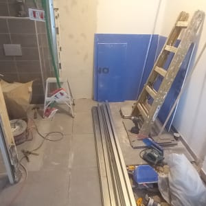 סולם, לוחות מתכת, כלי עבודה וחומרי בנייה בחדר בשיפוץ