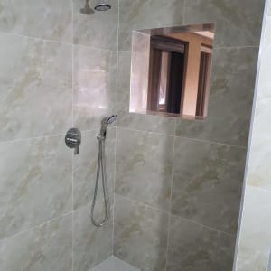 מקלחת חדשה עם אריחים אפורים וראש מקלחת מודרני