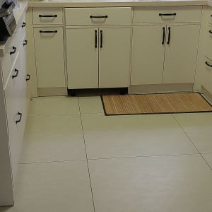 מטבח עם ארונות לבנים, כיור וברז, מוצרי ניקוי על השיש