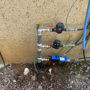 צינורות מים עם ברזים ומדי מים על קיר חיצוני