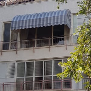 סוכך פסים כחול לבן על מרפסת בקומה עליונה