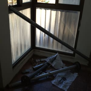 חלקי תריסים מונחים על הרצפה ליד חלון