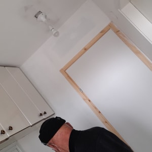 קיר גבס עם תיקון צבע ליד דלת עץ