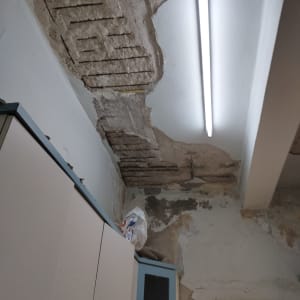 תקרה מתקלפת עם סימני רטיבות ותאורת פלורסנט