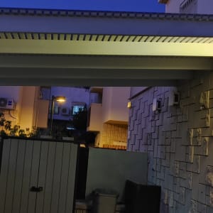 פרגולה מוארת עם קיר אבן וגדר עץ