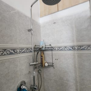 ראש מקלחת מתכת מותקן על קיר אריחים