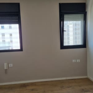 קיר עם שני חלונות, רצפת עץ ושקעי חשמל