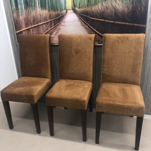 שלושה כיסאות מרופדים בבד חום על רקע תמונה