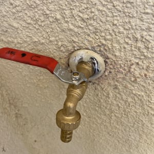 ברז פליז עם ידית אדומה על קיר