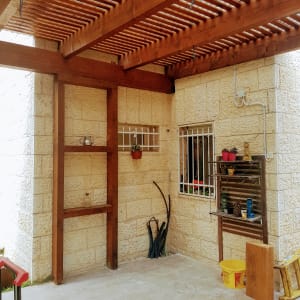 מדף עץ עם עציצים וכלי גינה ליד קיר אבן