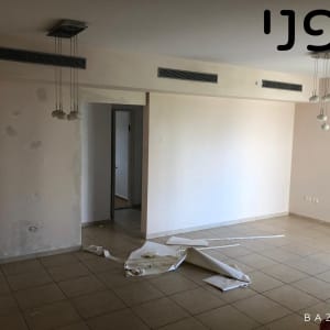 חדר ריק עם ניירות על הרצפה ותאורה תלויה