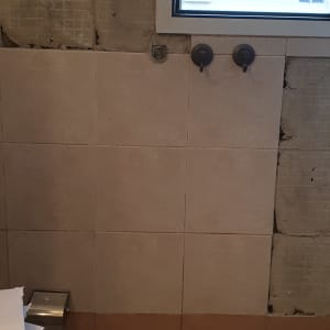 קיר עם אריחים חלקיים וחלון, שיפוץ בעיצומו