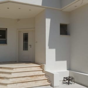 כניסה לבית עם מדרגות אבן ודלת לבנה