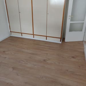 רצפת עץ חדשה בחדר עם ארון ודלת לבנה