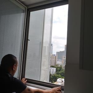 אדם מתקין חלון אלומיניום עם רשת