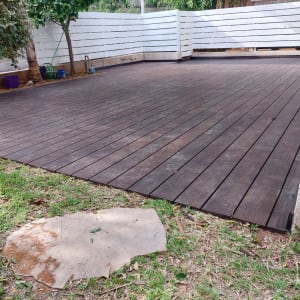 דק עץ חום בגינה עם גדר לבנה