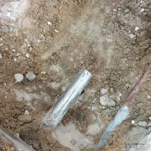 צינור מתכת חשוף באדמה עם חצץ