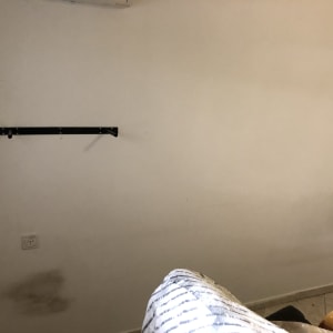 קיר לבן עם כתמים כהים ומדף שחור