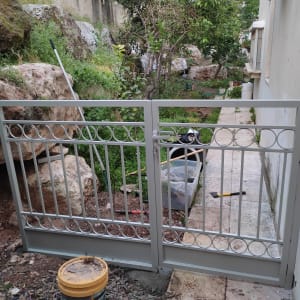 שער מתכת אפור עם עיטורים עגולים בגינה