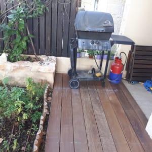 גריל גז על דק עץ ליד גינה קטנה