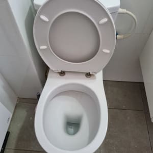 אסלה עם מכסה פתוח וצינור מים מחובר