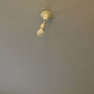 נורה חשמלית תלויה מהתקרה עם בית מנורה לבן