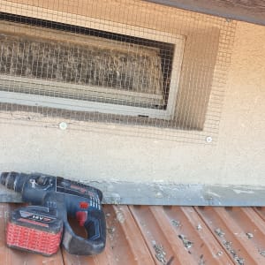 רשת מתכת מותקנת על חלון עם מקדחה על גג רעפים