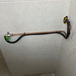 צינור גז עם שסתום ירוק על קיר אריחים