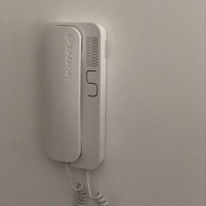 אינטרקום לבן עם שפופרת תלויה על הקיר