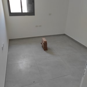 חדר ריק עם רצפה מלוכלכת ואריחים על הרצפה