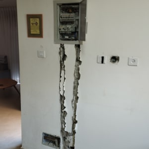 ארון חשמל פתוח עם חוטים חשופים בקיר