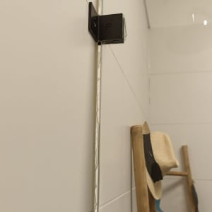 זכוכית מקלחון עם תפס שחור על קיר לבן