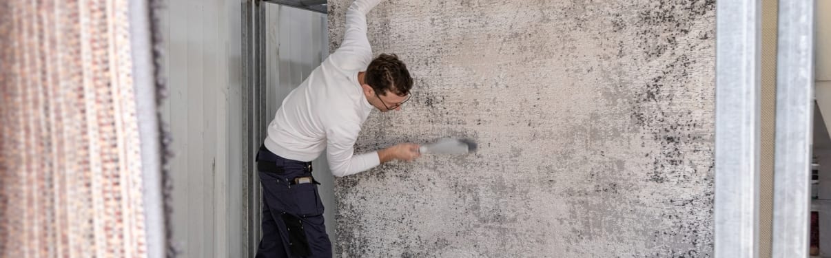 אדם מנקה שטיח עם מברשת במתקן מתכת