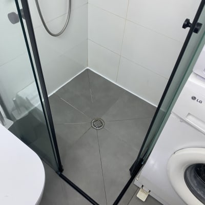 מקלחון עם רצפת אריחים ומכונת כביסה