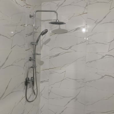 ראש מקלחת וכיור על קיר אריחים לבנים