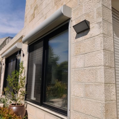 חלונות עם תריסים סגורים על קיר אבן חיצוני