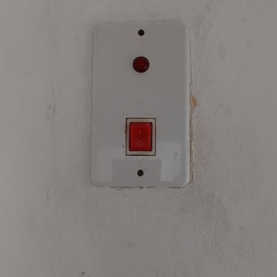 מתג חשמלי עם כפתור אדום על קיר לבן